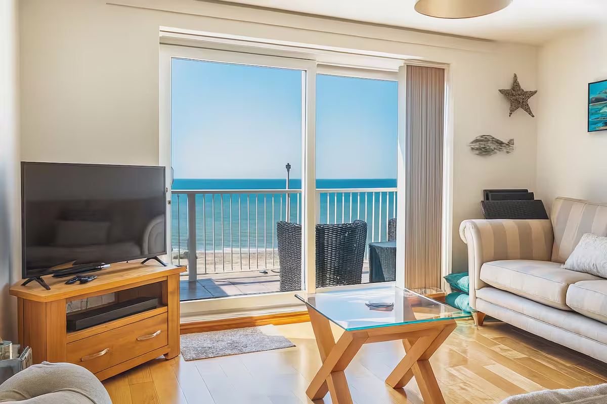 Four Degrees West – open-plan living room opening onto sea-view balcony