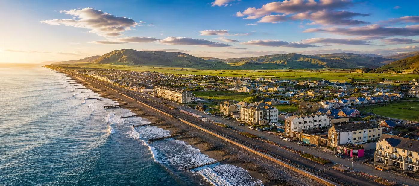 Aerial view of Tywyn seafront at golden hour, Cardigan Bay and mountains beyond, Mid-Wales